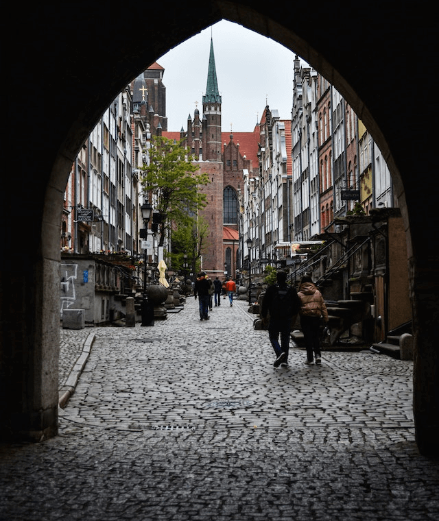 In this example, we convert a PNG image of a street in an old town, into a Data URI. The image is transformed into a fully textual format with a prefix indicating the encoding and extension as "image/png;base64". (Source: Pexels.)