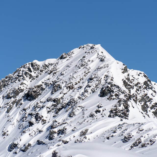 In this example, we use an additional feature of this tool, which allows creating transparent WebPs from opaque JPGs. The JPG photo that we're working with shows a rocky mountain covered in snow, standing against a clear blue sky. We enable the "Create a Transparent WebP" option and set the transparency color to the sky color, which is "rgba(69, 124, 180)". Additionally, we remove a range of 5% of similar blue sky shades. This combination of options removes the sky background from the JPG, creating a transparent WebP. Additionally, to make the output WebP usable in design, we also apply an anti-aliasing effect with a radius of 3px to the mountain ridge to ensure a seamless transition between the transparent sky and the opaque ridge. (Source: Pexels.)